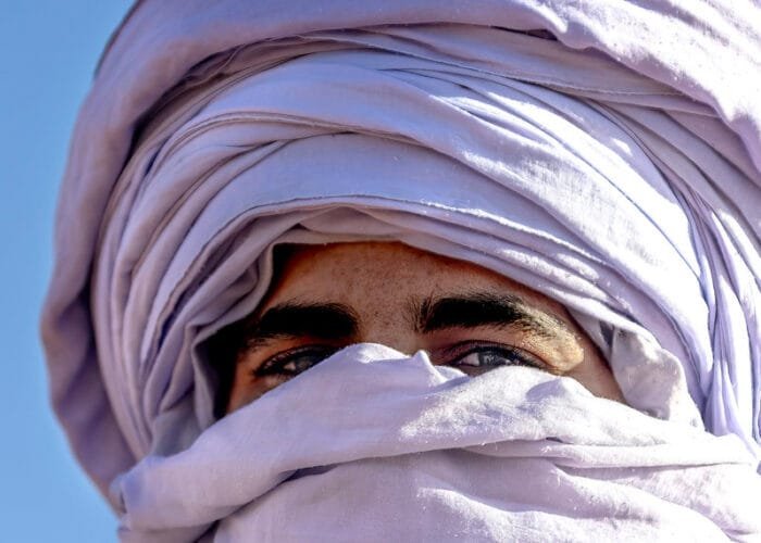 Man wearing a traditional Moroccan scarf in the desert`